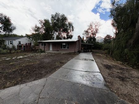 Sep 18, 2026. Front of the brick house, wet driveway, and the mountains behind the trees