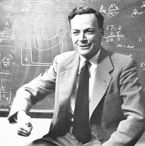 Richard Feynman smiling in front of a blackboard covered with equations, 1959.